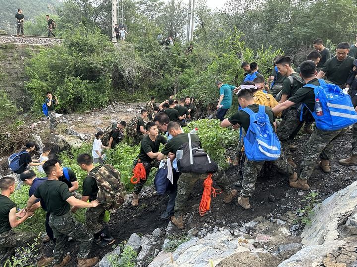 8月2日，Z180次受困列车的旅客在武警北京总队机动第三支队官兵的帮助下徒步前往转运客车（手机照片）。新华社记者 王艳刚 摄