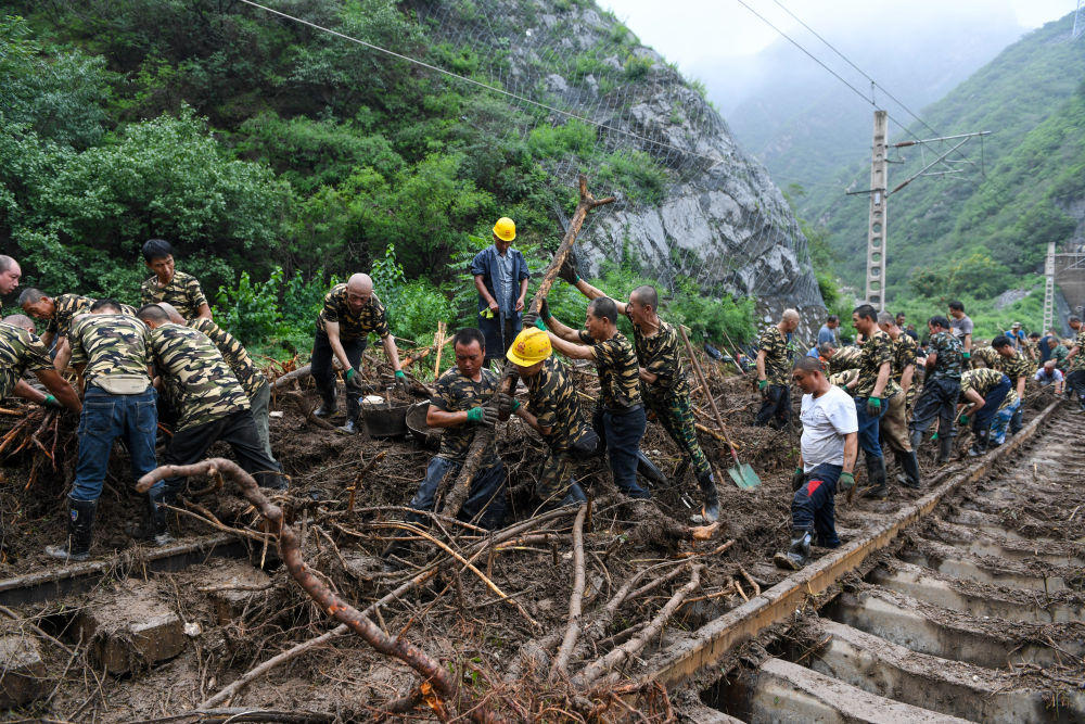 8月1日，在北京市门头沟区水峪嘴村附近一段被阻断的铁路线上，中铁六局工作人员在清理轨道上的杂物，全力恢复交通。新华社记者 鞠焕宗 摄